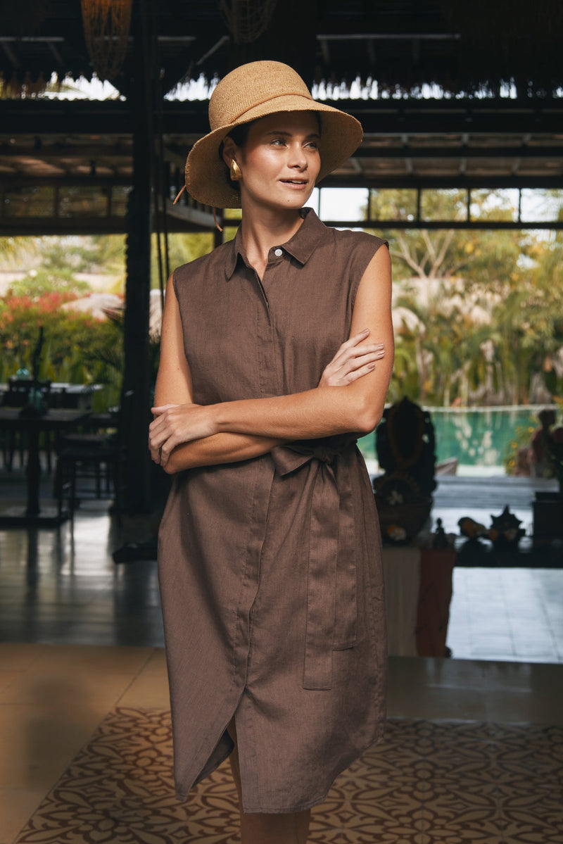 a woman wearing by the sea tropical hat and linen brown dress in luxury resort 
