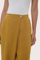 Close-up of the linen fabric texture and tailored detailing on the mustard pants