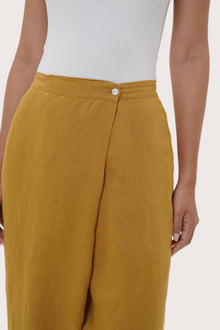 Close-up of the linen fabric texture and tailored detailing on the mustard pants