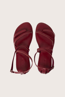 Astola sandal in red shown in a global view highlighting its full silhouette and refined resort design