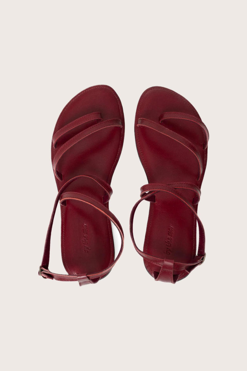 Astola sandal in red shown in a global view highlighting its full silhouette and refined resort design