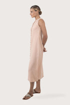 Side profile of the Ayu Linen Maxi Dress Pastel Pink showing its cut and natural movement