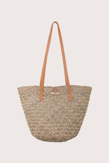 Beach bucket straw bag in natural woven finish styled as an elevated resort accessory, front view