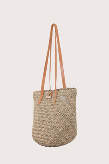 Side profile of beach bucket straw bag highlighting its soft structured bucket shape