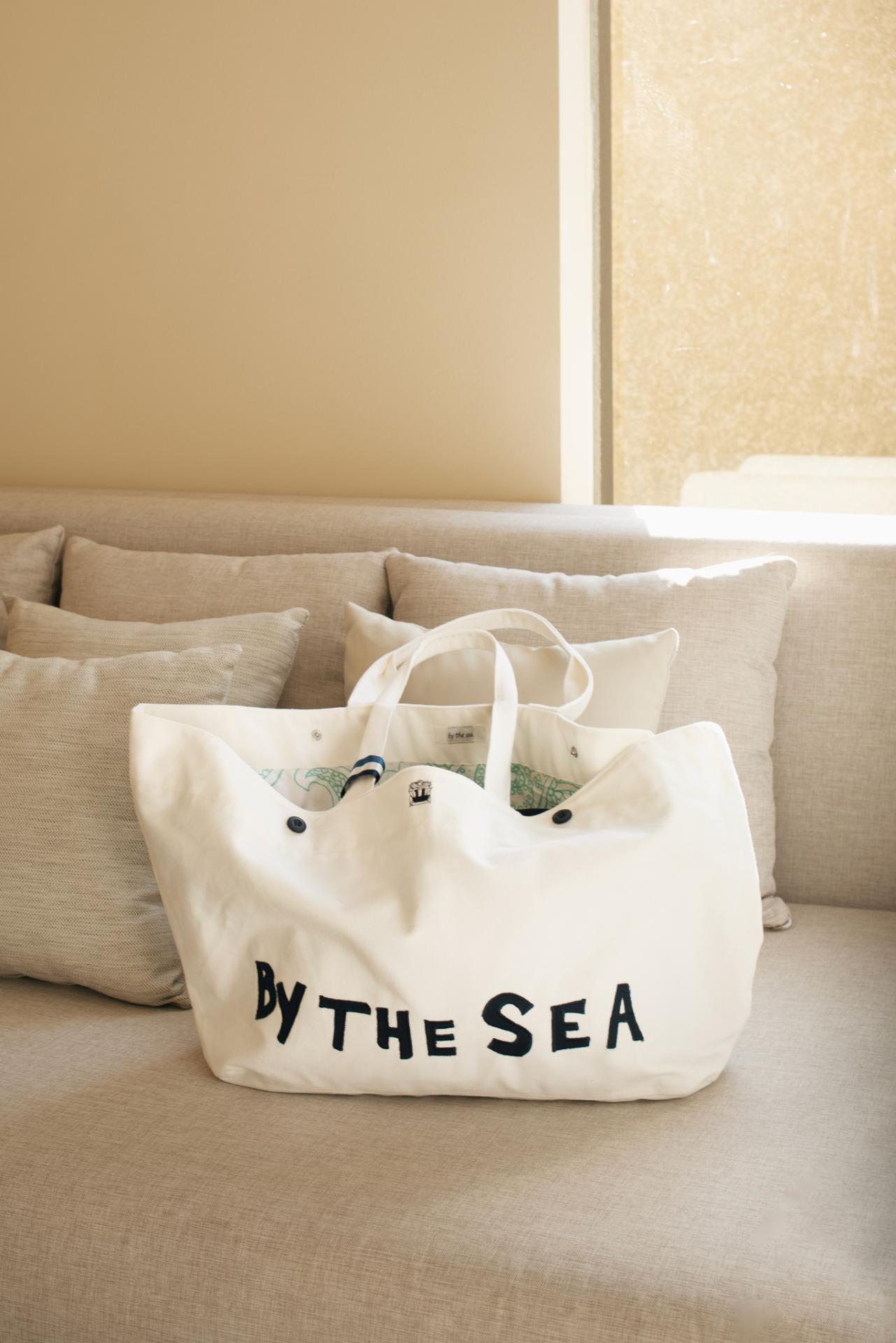 By The Sea beach bag styled with elegant resort outfit in a tropical seaside setting
