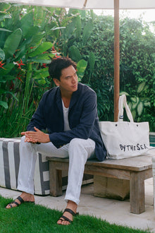 By The Sea beach bag captured in a full resort styling scene with coastal luxury aesthetic