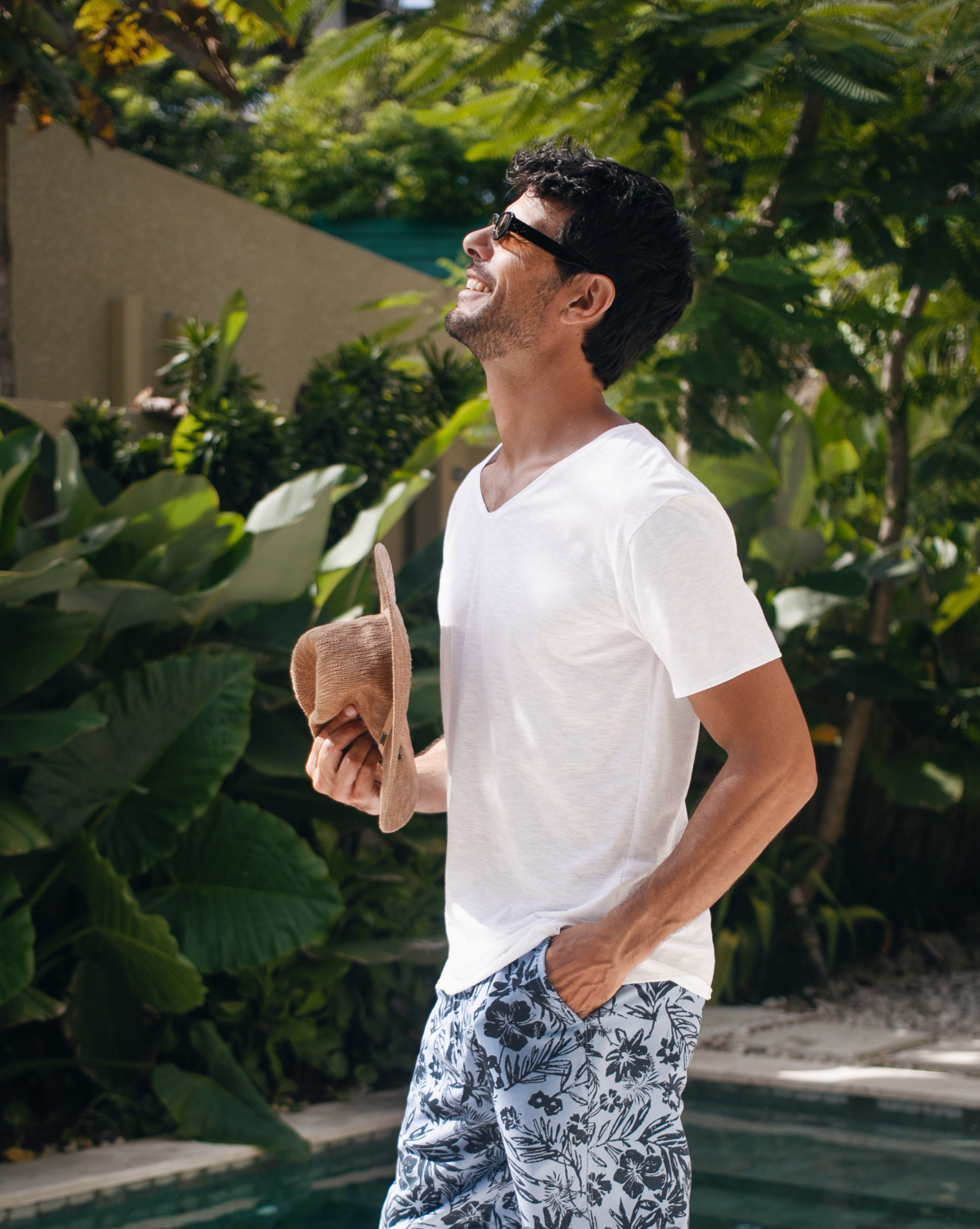 Men wearing white Tshirt and printed cotton bermuda holding Hat in Bali resort