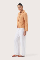 Side profile of the Cala Linen Blazer Orange showing its cut and natural movement