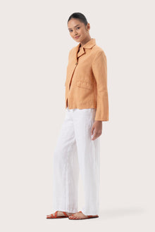 Side profile of the Cala Linen Blazer Orange showing its cut and natural movement