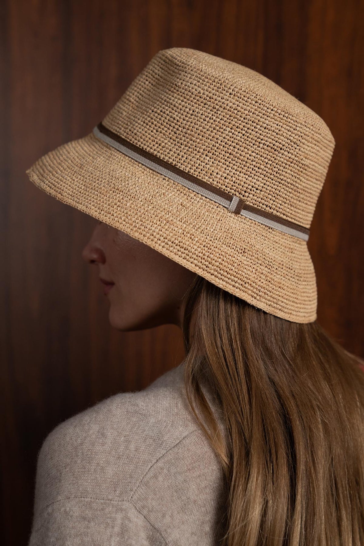 Woman wearing the natural straw Dewy hat with a brown ribbon in a tropical resort setting