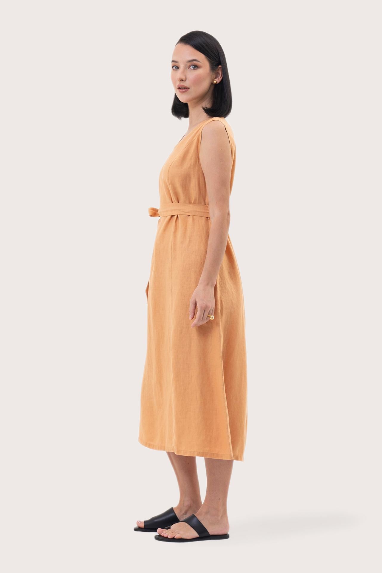 Side profile of the Eva Linen Midi Dress Light Orange showing its cut and natural movement