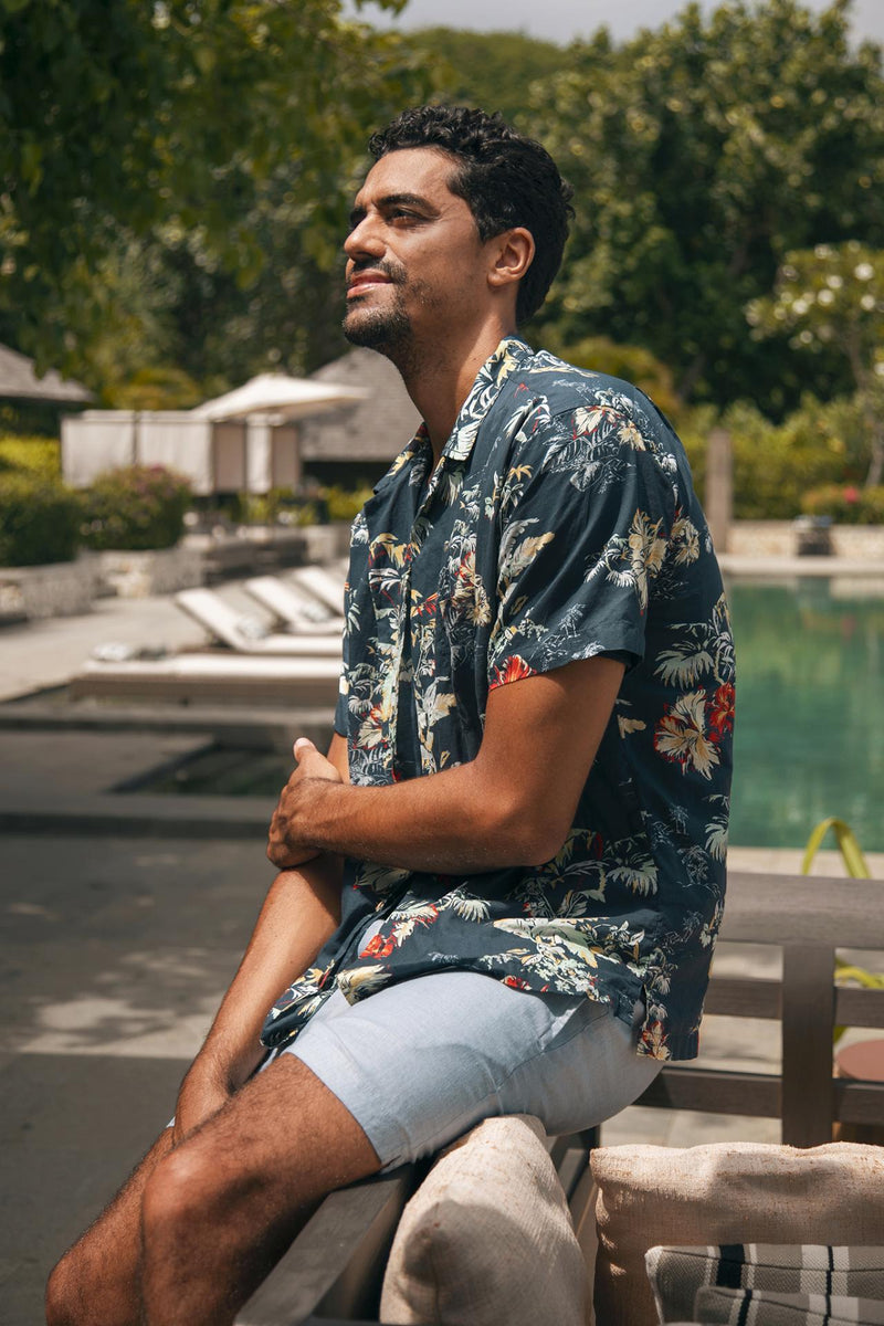 Model wearing the blue Gowa linen shorts in a tropical resort setting