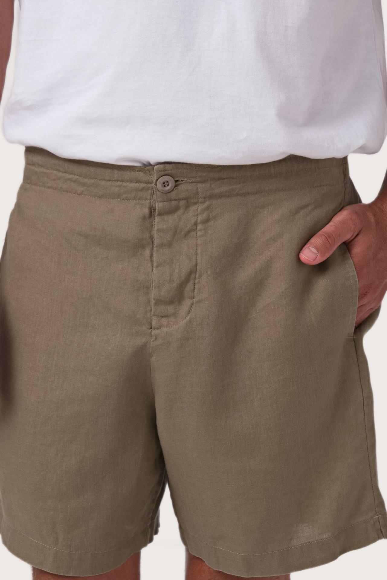 Close-up of the linen fabric texture and refined tailoring details on the olive shorts