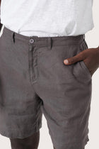 Close-up of the linen fabric texture and refined tailoring details on the grey brown bermuda shorts