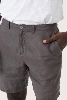 Close-up of the linen fabric texture and refined tailoring details on the grey brown bermuda shorts