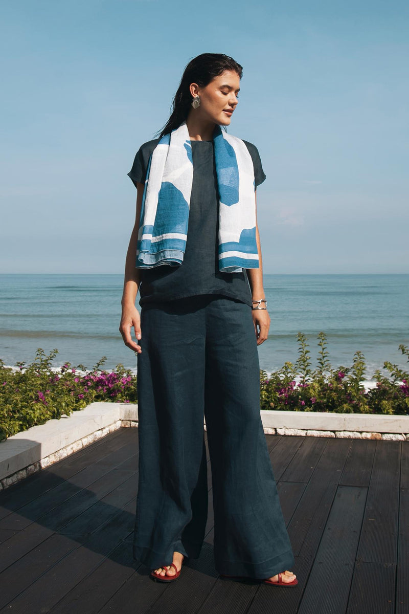 Model wearing navy linen wide-leg pants in a tropical resort setting