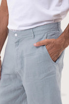 Close-up of the linen fabric texture and refined tailoring details on the light blue bermuda shorts