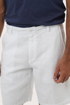Close-up of the linen fabric texture and refined tailoring details on the white bermuda shorts