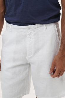 Close-up of the linen fabric texture and refined tailoring details on the white bermuda shorts