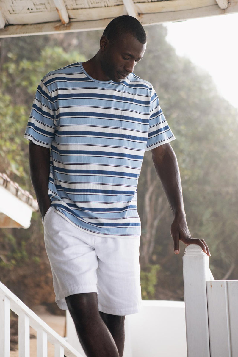 Model wearing the white linen Bermuda shorts in a tropical resort setting