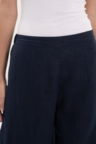 Close-up of the linen fabric texture and tailored details on the navy pants