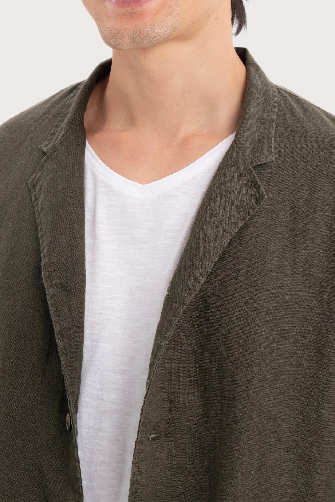 Close-up of the linen fabric texture and refined tailoring details on the dark green jacket