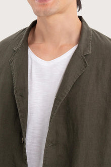 Close-up of the linen fabric texture and refined tailoring details on the dark green jacket