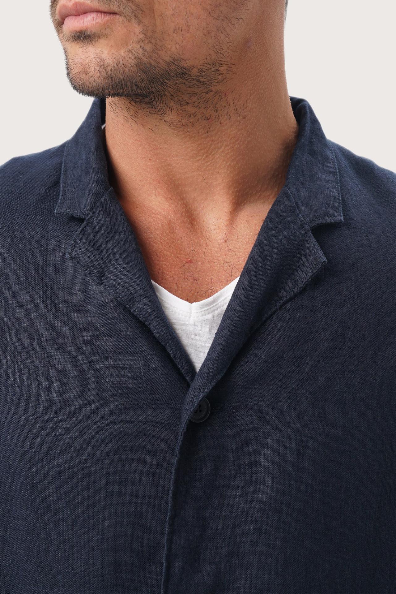 Close-up of the linen fabric texture and refined tailoring details on the navy blue jacket