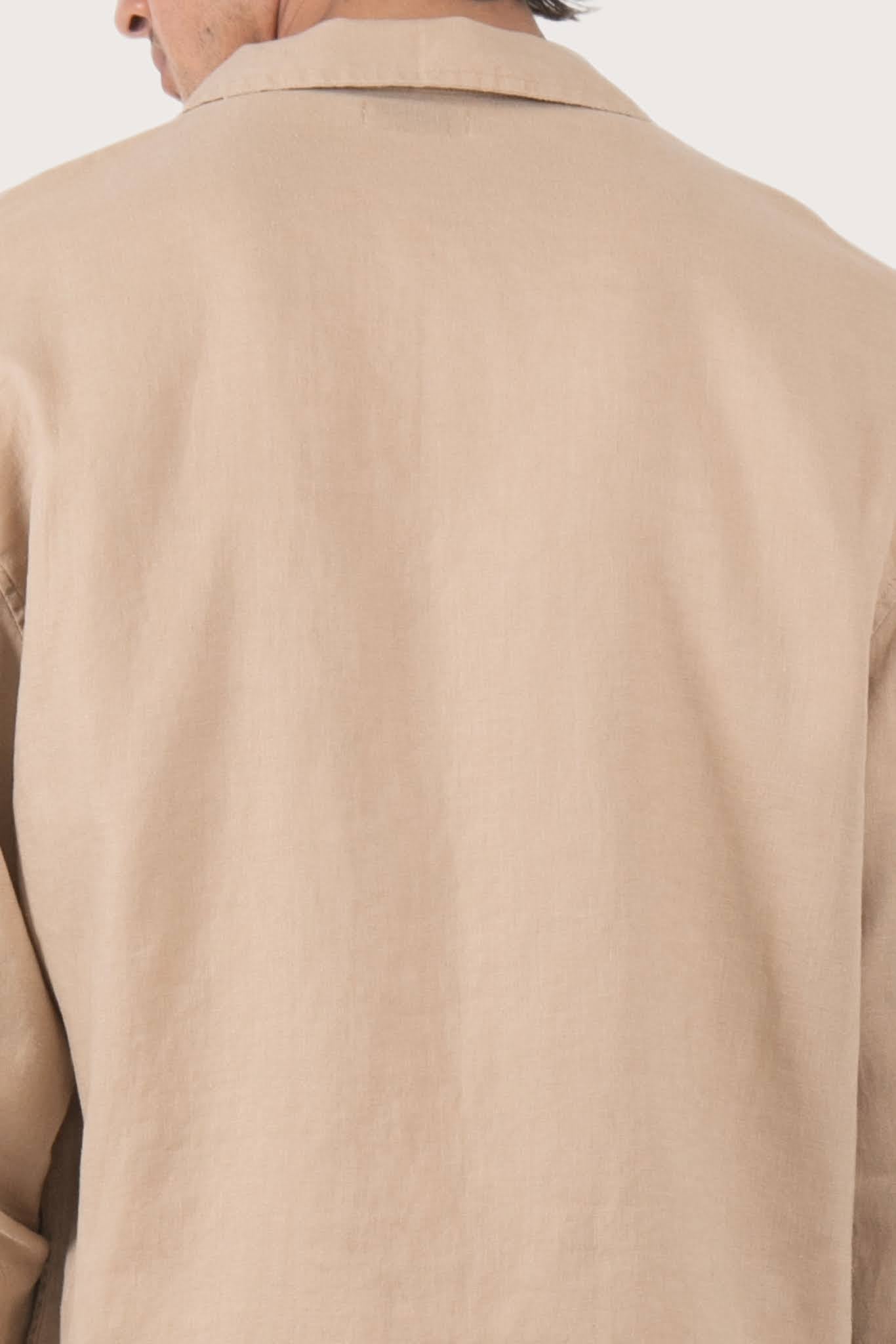 Close-up of the linen fabric texture and refined tailoring details on the creme jacket