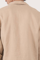Close-up of the linen fabric texture and refined tailoring details on the creme jacket