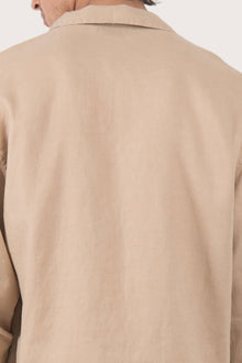 Close-up of the linen fabric texture and refined tailoring details on the creme jacket