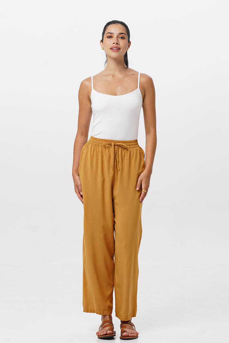 Woman wearing the Maya Drawstring Pants Mustard designed for effortless resortwear and tropical living by By The Sea Bali.