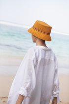 Luxury resort styling featuring the Moa Raffia Bucket Hat Tangerine in a tropical coastal setting