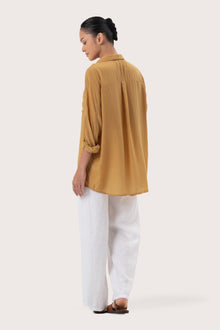 Back view of the Muara Shirt Mustard highlighting the garment shape and drape.