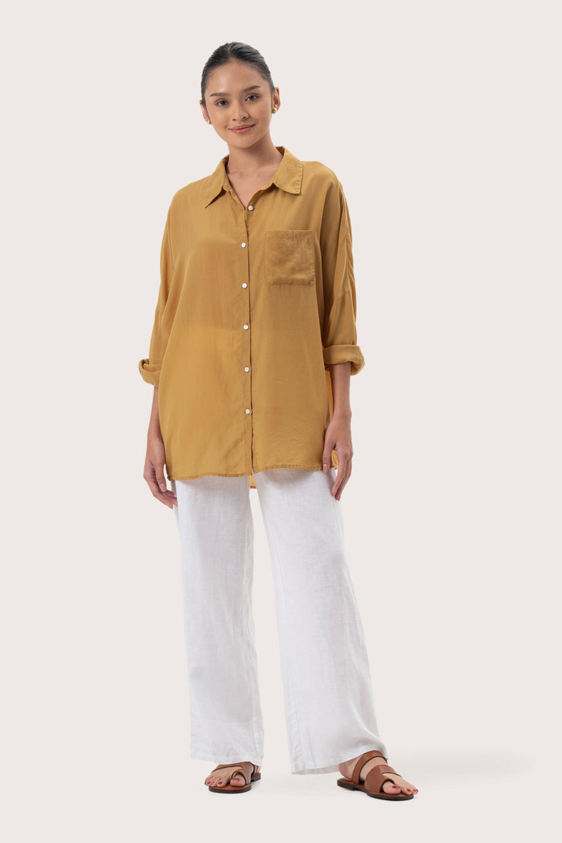 Woman wearing the Muara Shirt Mustard designed for effortless resortwear and tropical living by By The Sea Bali.