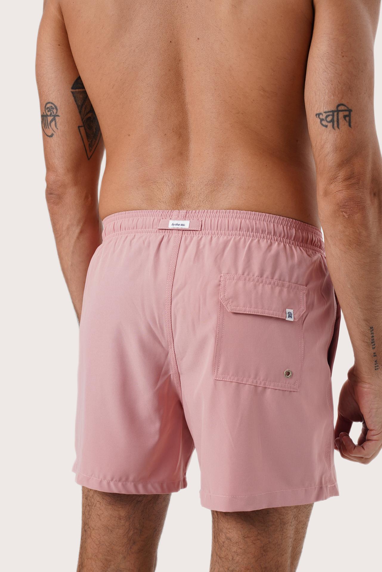 Men's beachwear styling featuring the Paco Swim Trunk in Pastel Pink by By The Sea Bali