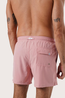 Men's beachwear styling featuring the Paco Swim Trunk in Pastel Pink by By The Sea Bali