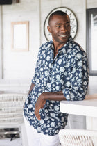 Model wearing the navy Garden Flower Panta cotton shirt in a tropical resort setting