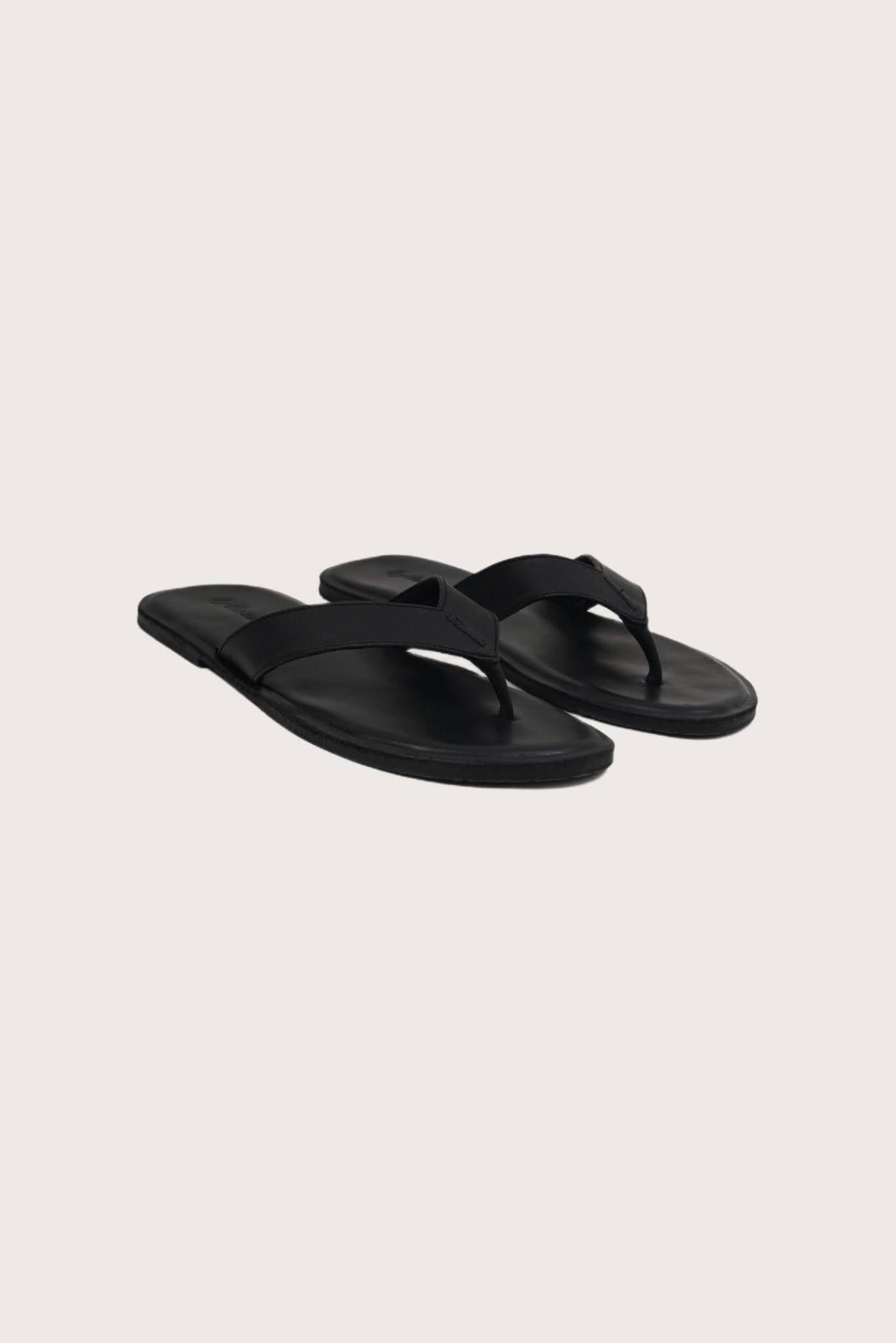 Paros leather sandals in nero front view showcasing elegant leather straps and minimalist resort aesthetic