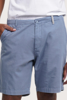 Close-up of the fabric texture and refined tailoring details on the light blue bermuda shorts
