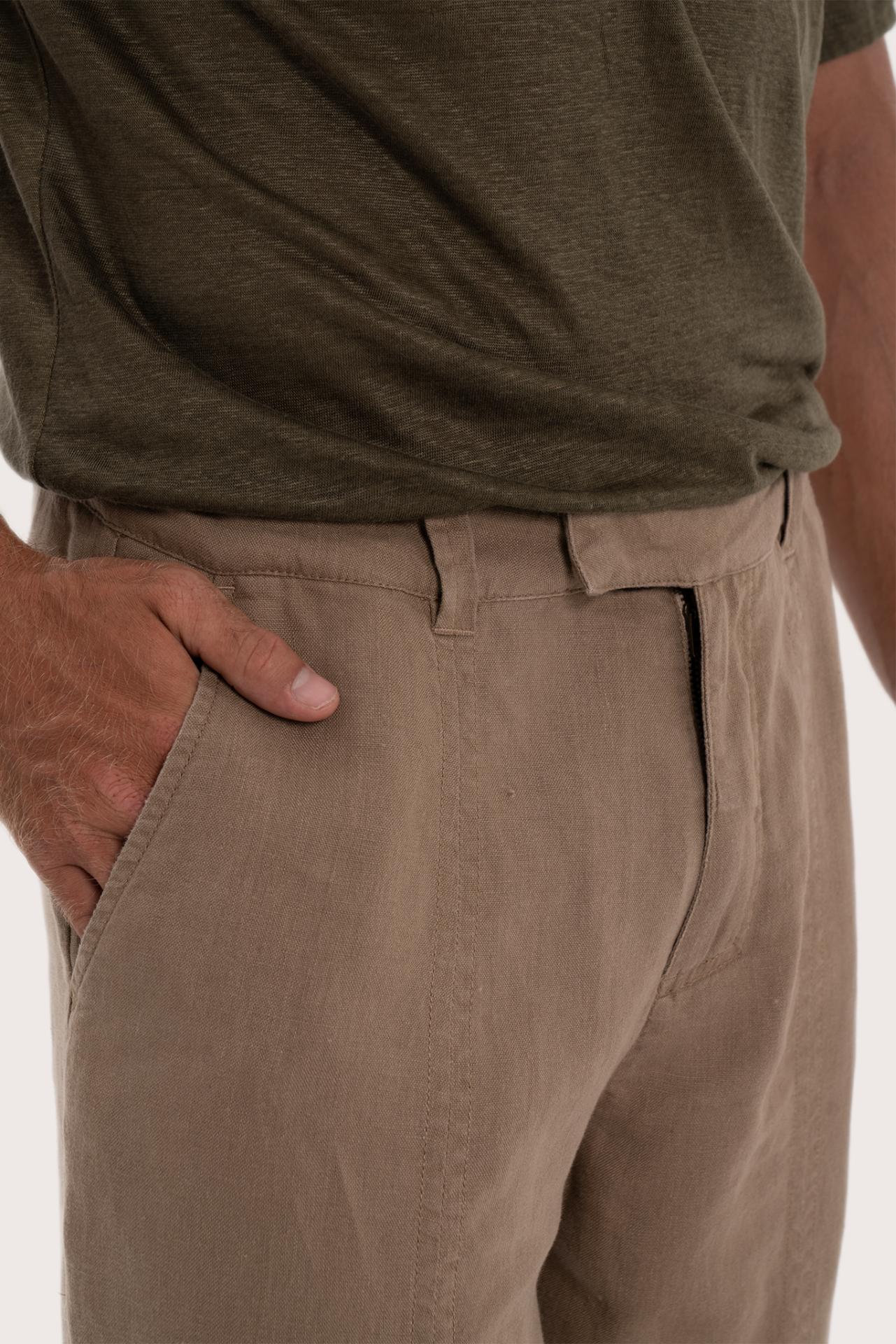 Close-up of the linen fabric texture and tailored detailing on the cream pants