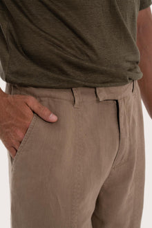 Close-up of the linen fabric texture and tailored detailing on the cream pants
