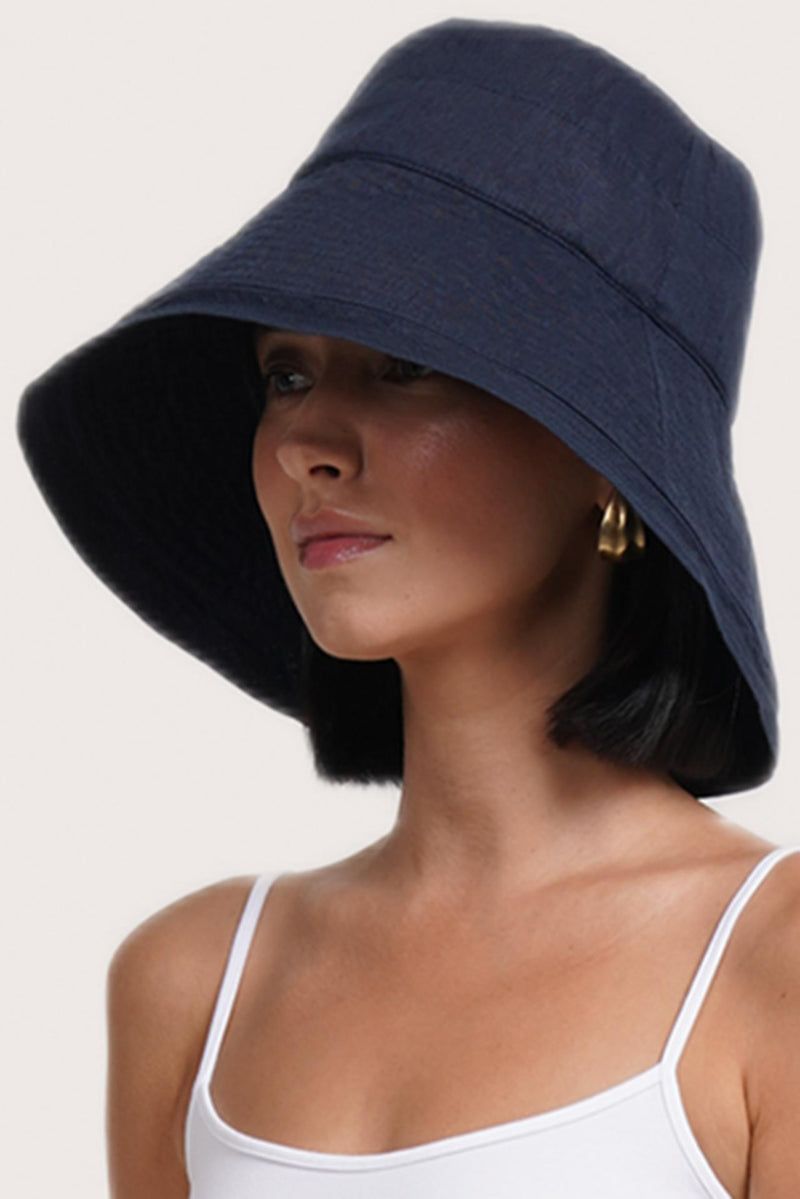 Luxury resort styling featuring the Savanna Linen Hat Navy in a coastal tropical setting