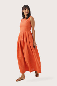 Side profile of the Shino Maxi Dress Orange showing its cut and natural movement