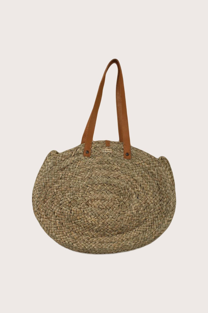 Straw round bag in natural woven finish styled as a refined resort accessory