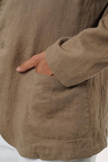 Close-up of the linen fabric texture and tailored details on the brown blazer
