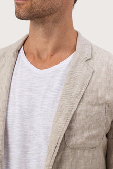 Close-up of the linen fabric texture and refined tailoring details on the crema jacket