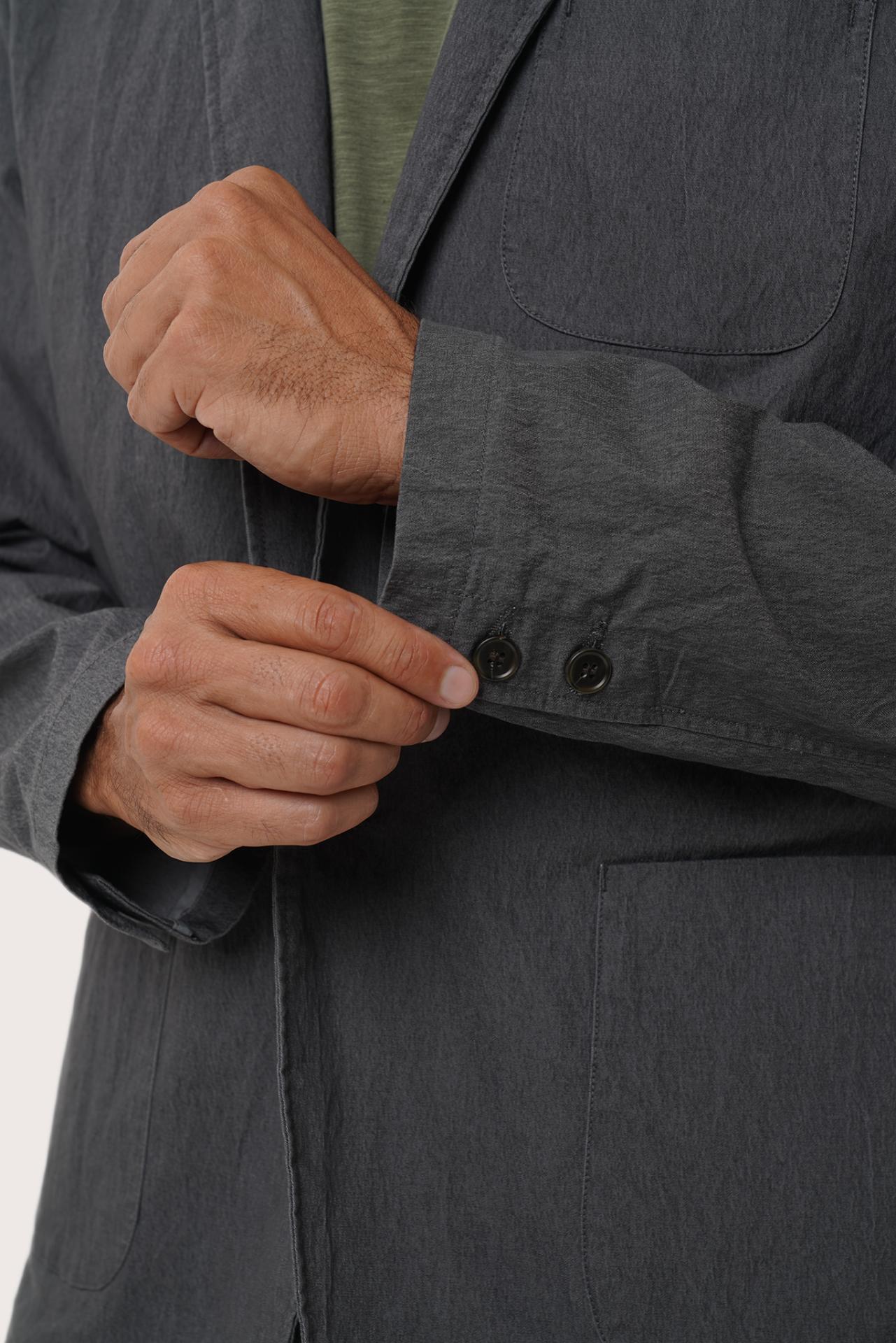 Close-up of the cotton polyester spandex fabric texture and tailored detailing on the dark grey blazer
