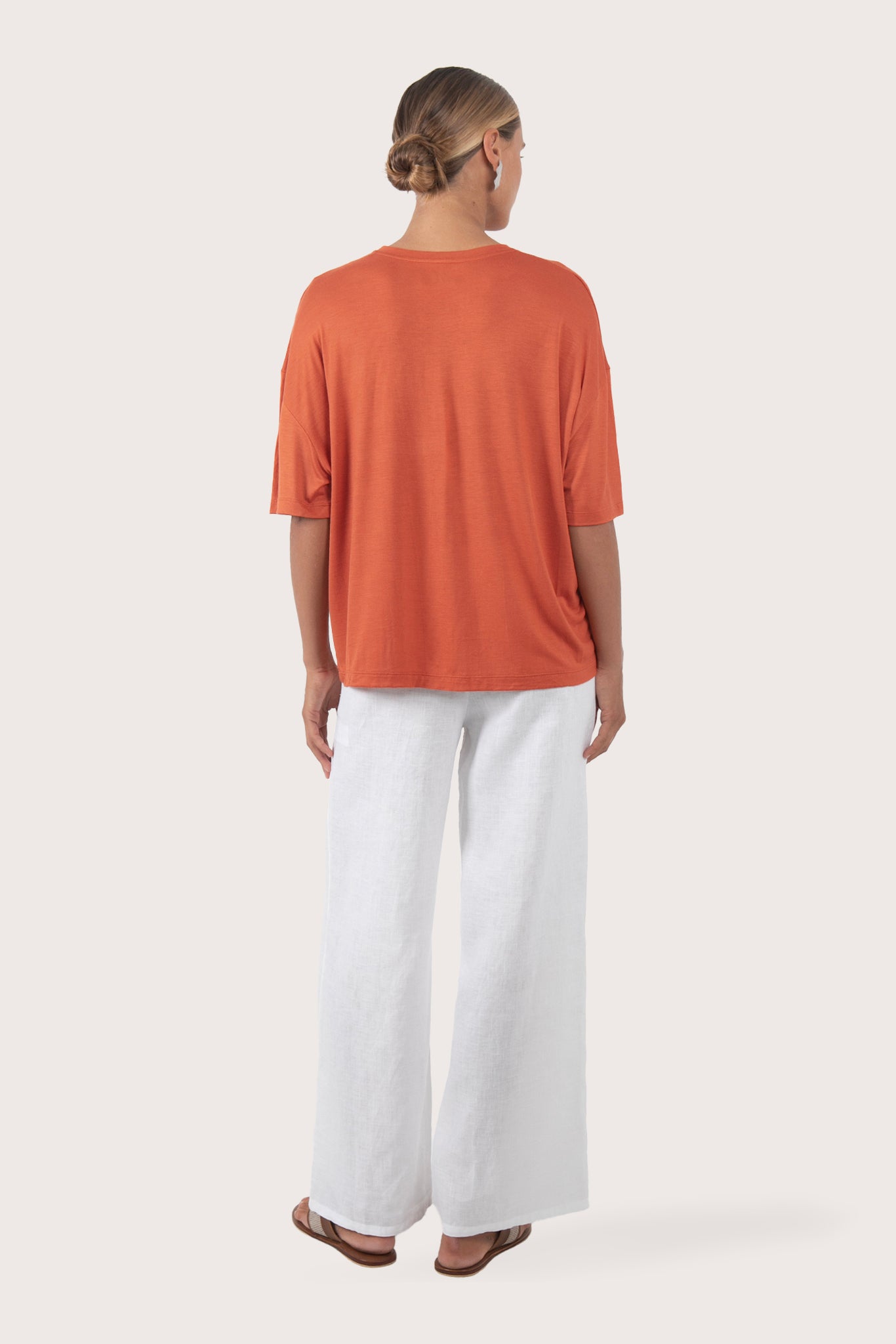 Back view of the Yara Top Orange highlighting the garment shape and drape.