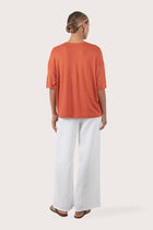 Back view of the Yara Top Orange highlighting the garment shape and drape.